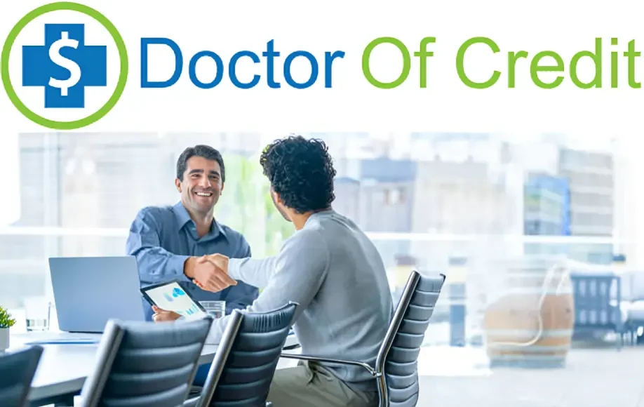 DoctorOfCredit handshake between two men in office meeting with laptop and tablet.