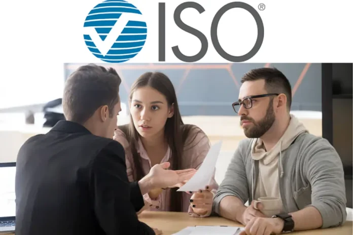 ISO ClaimSearch logo above three people sitting at a desk discussing paperwork in an office setting.