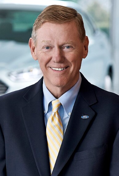 Former Ford CEO Alan Mulally smiling in a Ford showroom in 2013.
