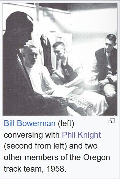 Black-and-white 1958 photo of University of Oregon track coach Bill Bowerman talking with Phil Knight and two other members of the Oregon track team in a locker room.