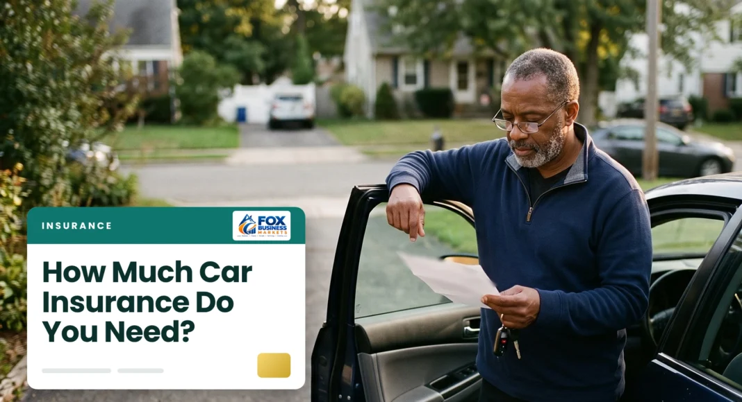 How Much Car Insurance Do You Need Man reviewing how much car insurance he needs beside his open car door in a suburban driveway