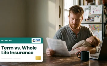 Term vs. Whole Life Insurance: Which One Is Right for You? Father holding a sleeping baby while reading life insurance papers at a kitchen table