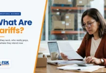 What Are Tariffs? How They Work, Who Pays, and Where They Stand Now What are tariffs explained: small business owner reviewing an import duty invoice with a calculator in her warehouse office