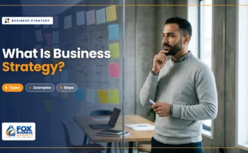 What Is Business Strategy? Types, Examples, and How to Build One What is business strategy featured image showing a business owner planning strategy at a glass wall with sticky notes